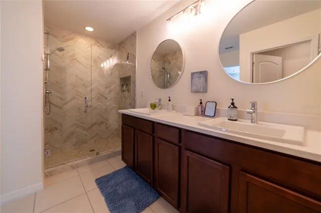a bathroom with a double vanity sink mirror and shower