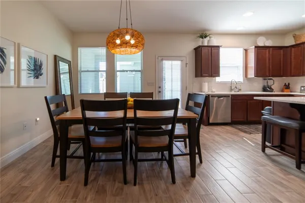 a dining room with wooden floor a chandelier a wooden table and chairs