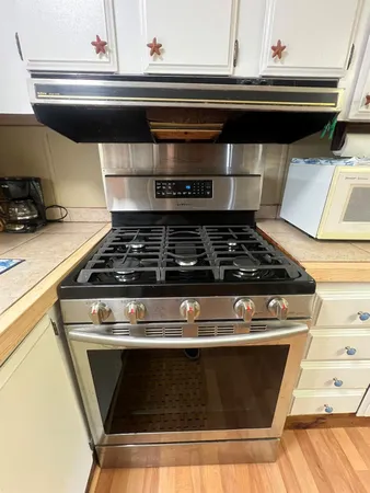 a stove top oven sitting inside of a kitchen