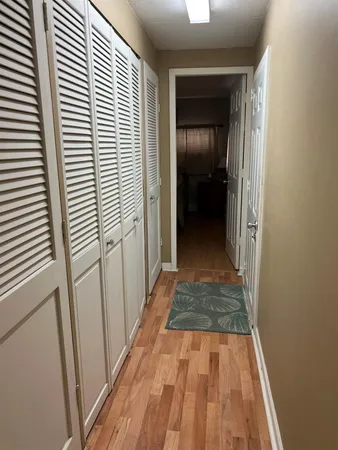 a view of a hallway with wooden floor and a bathroom