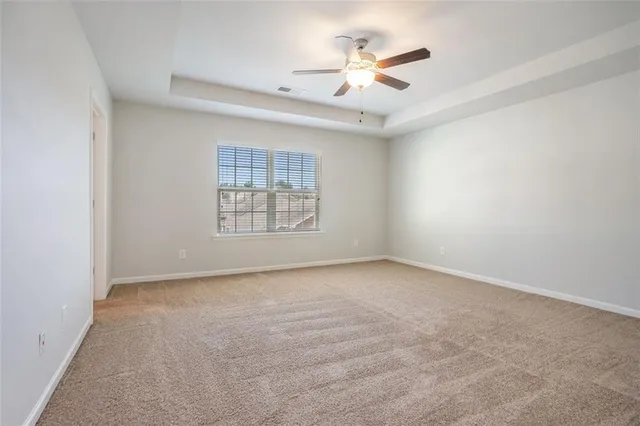 an empty room with windows and ceiling fan