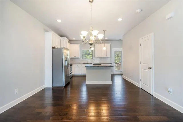 a view of a kitchen with refrigerator and wooden floor