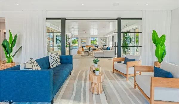 a living room with furniture large windows and wooden floor