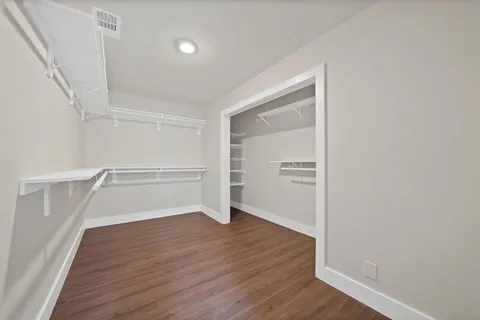 a view of an empty walk in closet with wooden floor