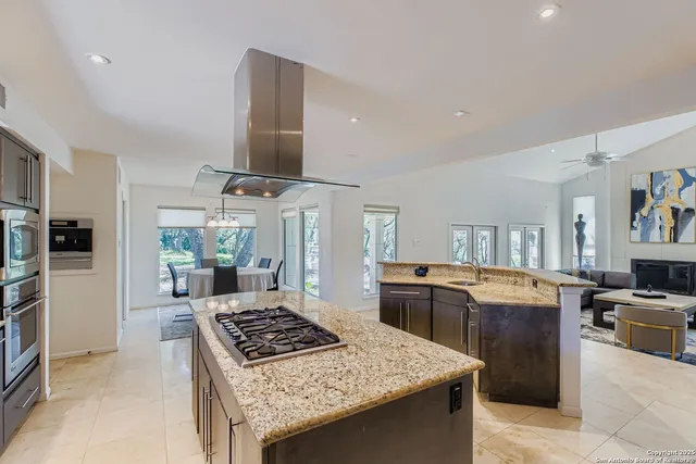 a kitchen with stainless steel appliances granite countertop a stove top oven a sink dishwasher and a refrigerator with wooden floor