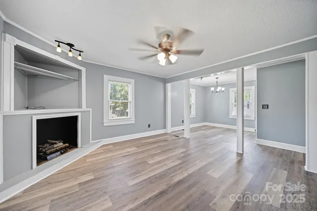 a view of livingroom with a fireplace wooden floor and chandelier
