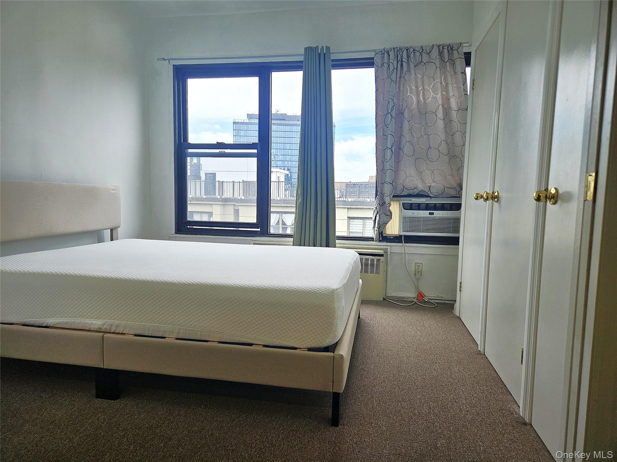 98-25 64th Road, Unit 8F Queens, NY 11374 - Photo 6 of 8 a bed sitting in a spacious bedroom next to a window