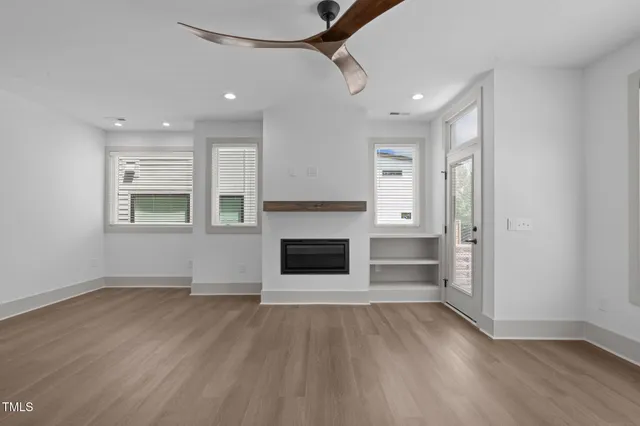 an empty room with windows and fireplace