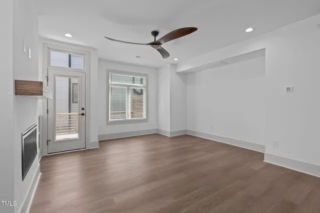 a view of an empty room with a window and wooden floor