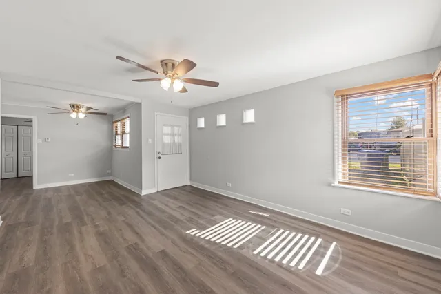 a view of an empty room with window and wooden floor