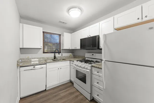 a kitchen with a sink white cabinets and white appliances