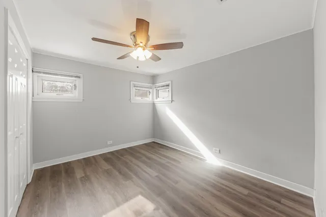an empty room with wooden floor fan and windows