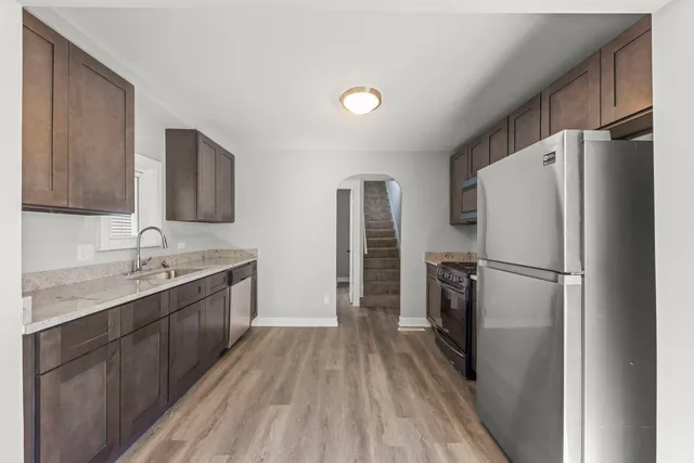 a kitchen with a refrigerator a sink and dishwasher with wooden floor