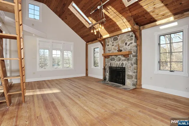 a view of an empty room with wooden floor fireplace and a window