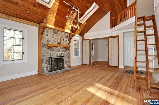 a view of an empty room with wooden floor fireplace and a window