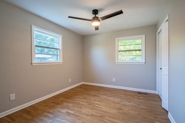 a view of an empty room with a window and wooden floor