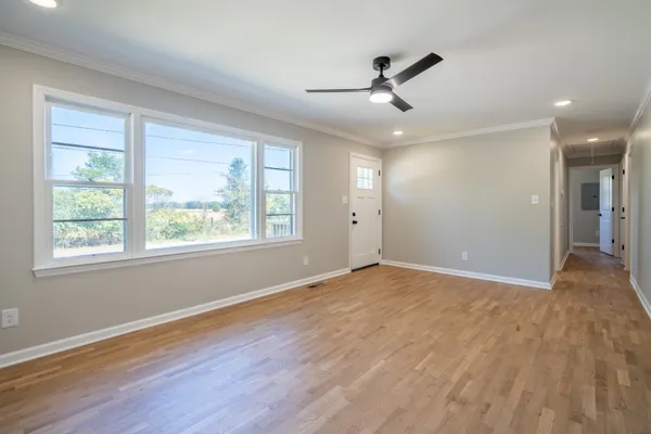 a view of an empty room with wooden floor and a window
