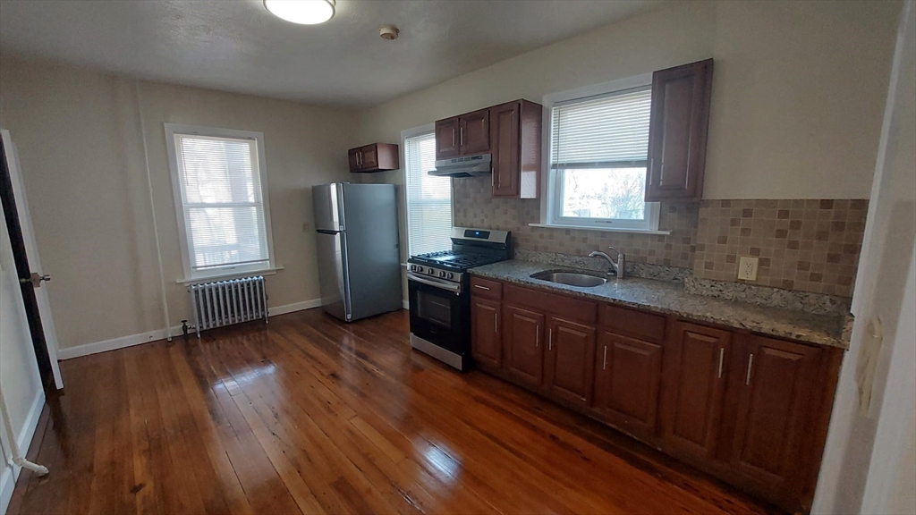 35 Catawba Street, Unit 2 Boston, MA 02119 - Photo 3 of 14 a kitchen with stainless steel appliances granite countertop wooden floors wooden cabinets a sink and a window