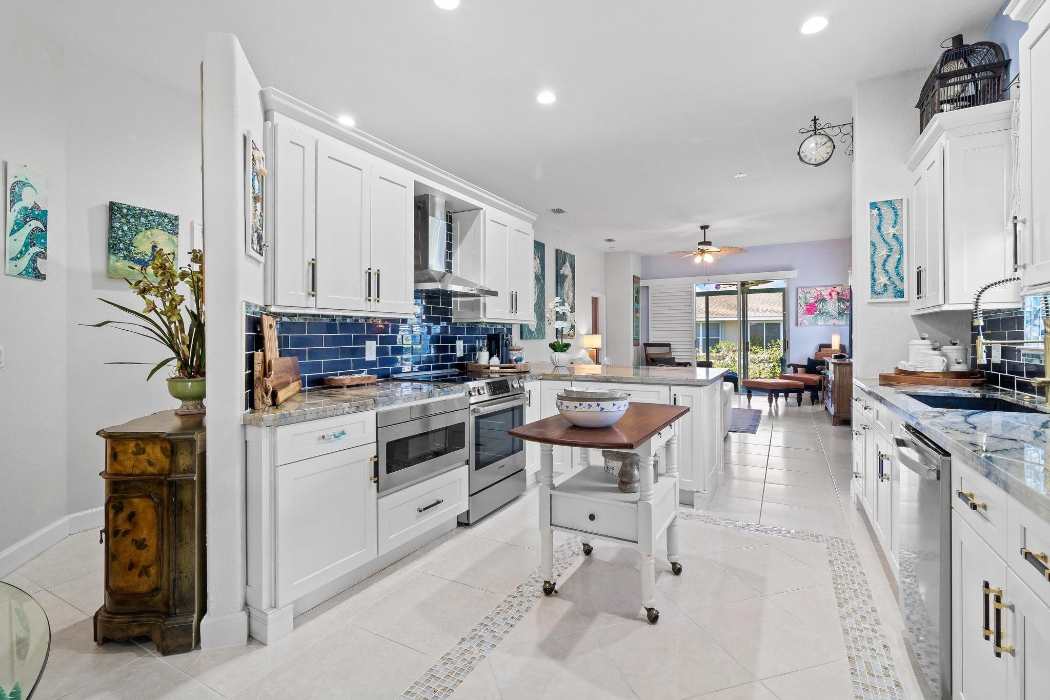 3017 Ocelot Way Fort Pierce, FL 34949 - Photo 12 of 20 a kitchen with stainless steel appliances kitchen island granite countertop a table chairs sink and cabinets