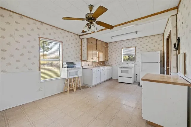 a large white kitchen with stainless steel appliances granite countertop a stove a sink and a refrigerator