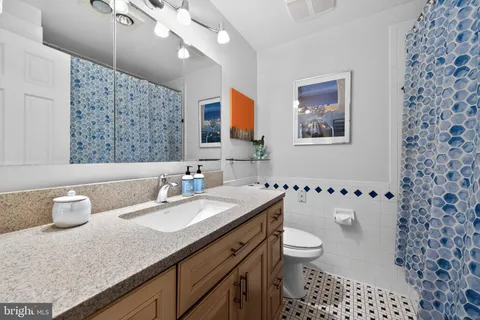 a bathroom with a granite countertop sink a toilet a mirror a vanity and shower