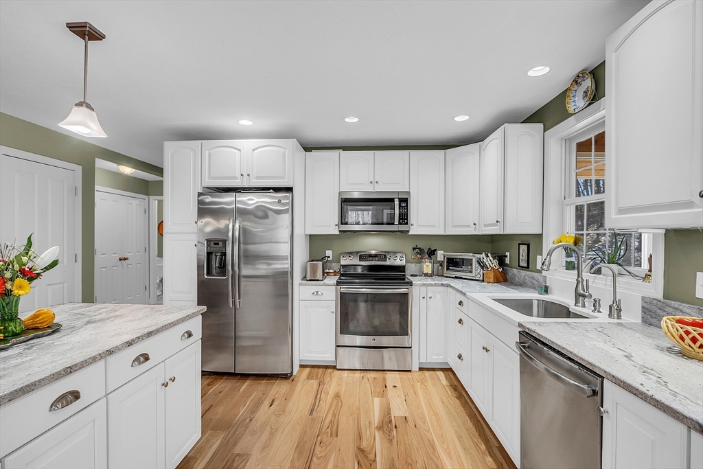 862 Reservoir Road Lunenburg, MA 01462 - Photo 19 of 37 a kitchen with granite countertop a refrigerator a sink dishwasher a stove and white cabinets with wooden floor