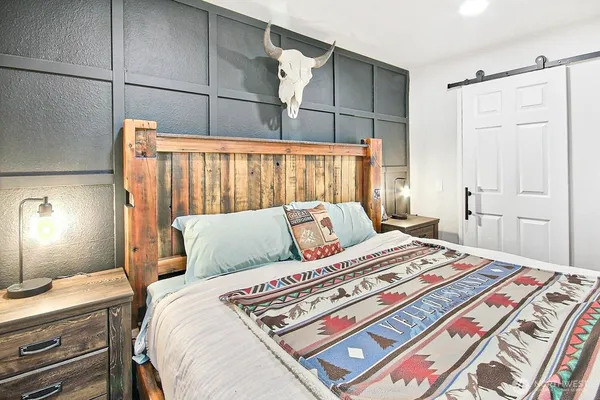 a bedroom with a bed and a lamp on dresser