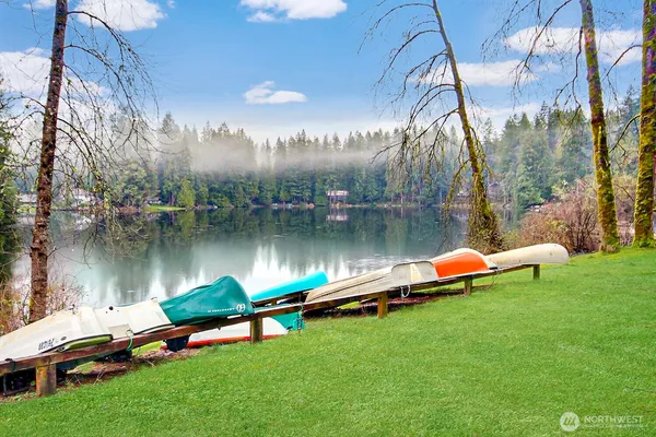 a view of a lake with lawn chairs and a table