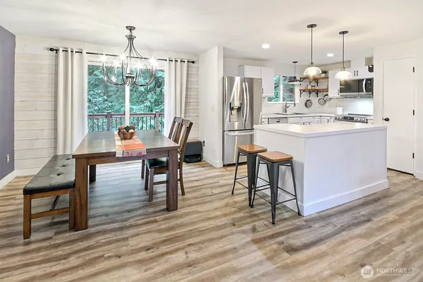a living room with stainless steel appliances kitchen island granite countertop furniture and a wooden floor
