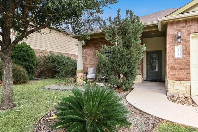 a view of a house with a small yard plants and large tree