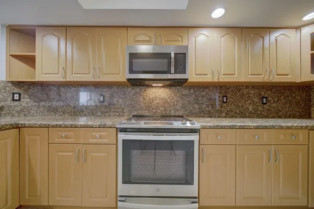 a kitchen with granite countertop white cabinets and stainless steel appliances