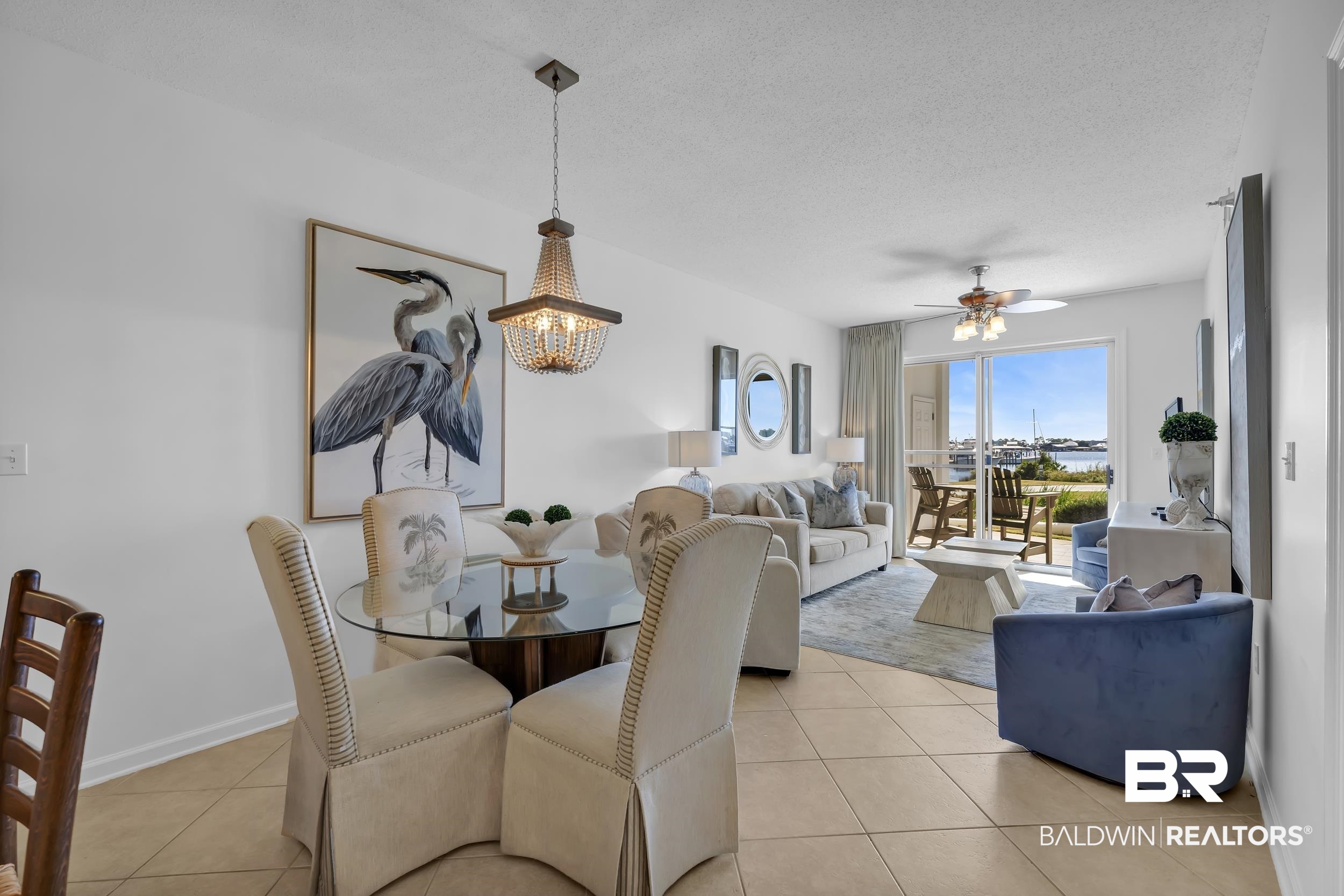 27282 Canal Road, Unit 104 Orange Beach, AL 36561 - Photo 19 of 79 Dining area featuring light tile patterned floors, a textured ceiling, a ceiling fan, and a chandelier