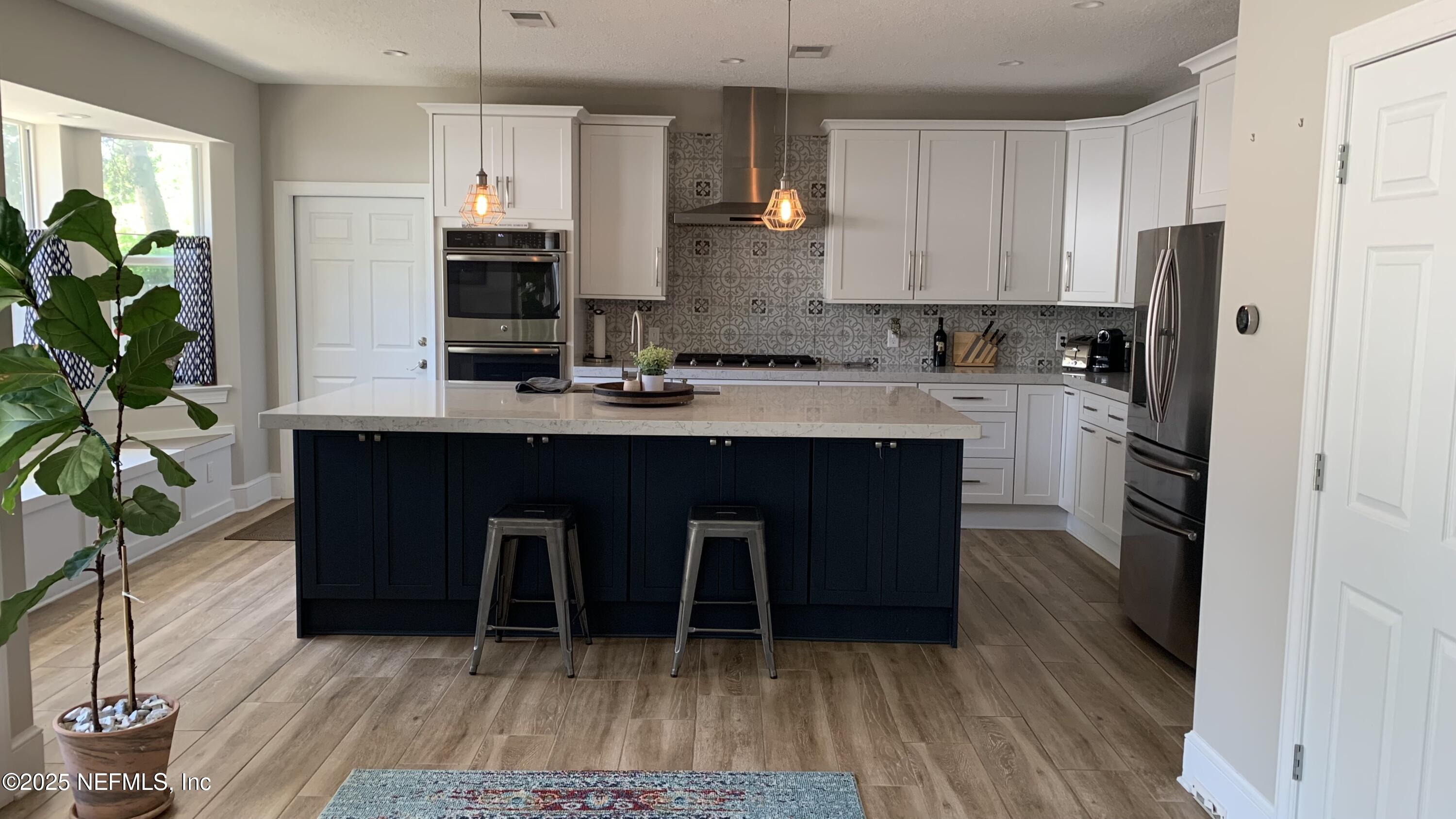 a kitchen with kitchen island a counter top space a sink a refrigerator and a potted plant