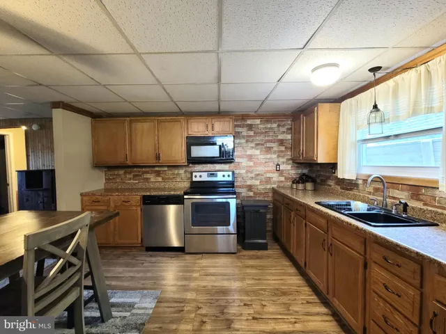 a kitchen with stainless steel appliances granite countertop a sink a stove and a wooden cabinets