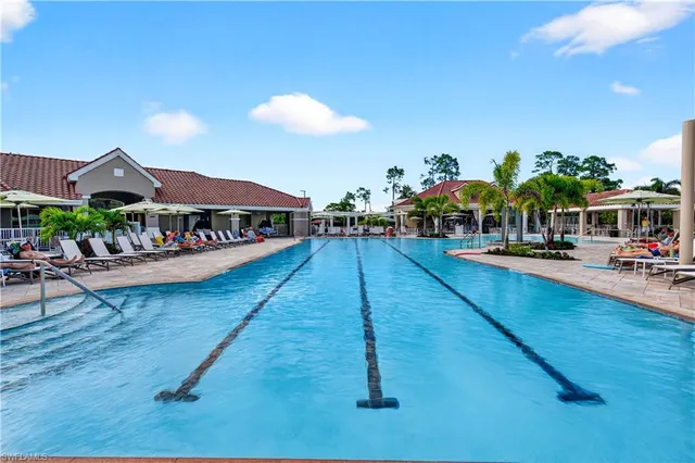 a view of a swimming pool with tables and chairs under an umbrella