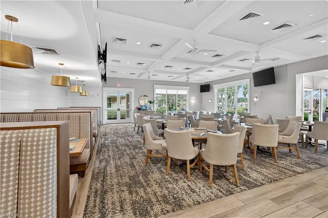 a room with lots of tables a large window and chairs