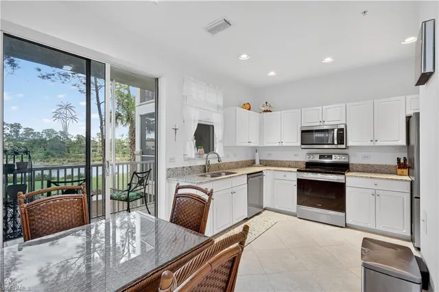 a kitchen with stainless steel appliances granite countertop a stove top oven a sink dishwasher a dining table and chairs with wooden floor