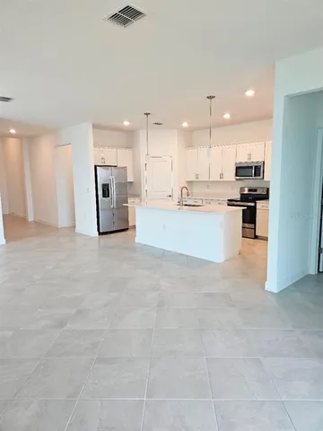 a large white kitchen with kitchen island a stove a sink a refrigerator and white cabinets