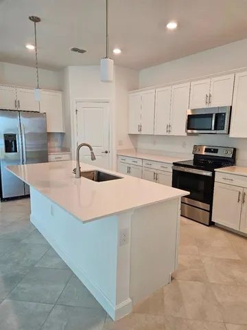 a kitchen with kitchen island a sink stainless steel appliances and cabinets