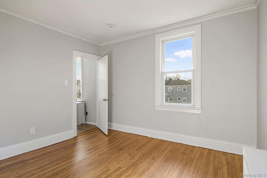 135 Webster Avenue, Unit 2 Harrison, NY 10528 - Photo 23 of 25 an empty room with wooden floor and windows