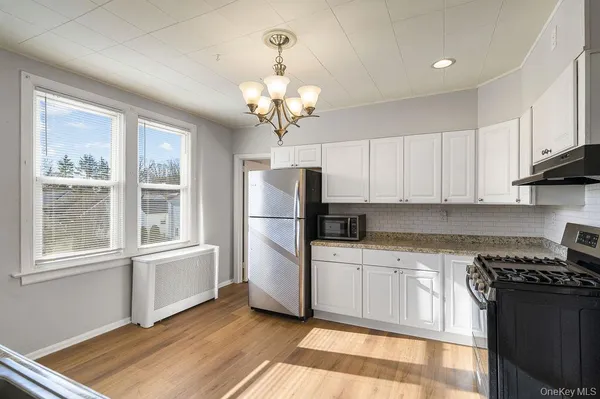 a kitchen with stainless steel appliances granite countertop a refrigerator a sink dishwasher a stove and white countertops with wooden floor