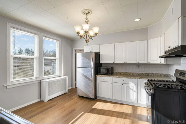 a kitchen with stainless steel appliances granite countertop a refrigerator a sink dishwasher a stove and white countertops with wooden floor