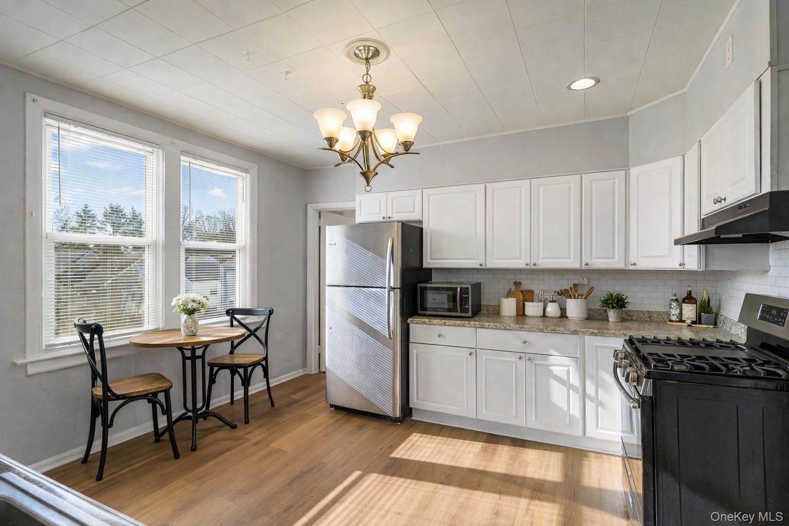 135 Webster Avenue, Unit 2 Harrison, NY 10528 - Photo 6 of 25 a kitchen with stainless steel appliances a table chairs and a refrigerator