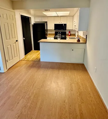 a view of kitchen with stainless steel appliances wooden floor and chair