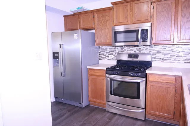 a kitchen with granite countertop cabinets stainless steel appliances and a wooden floor
