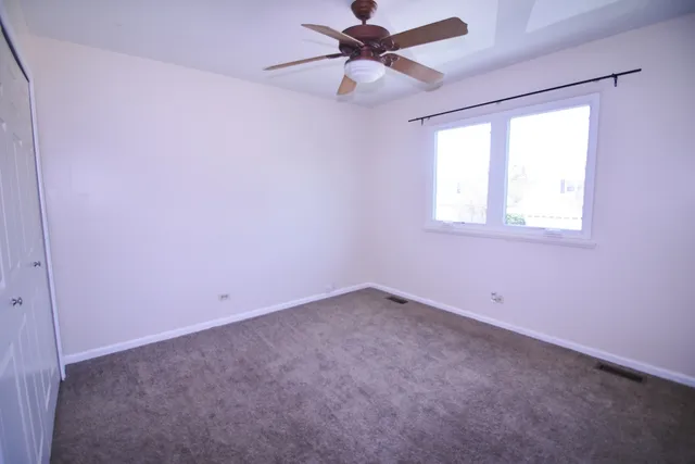 an empty room with a window and a fan
