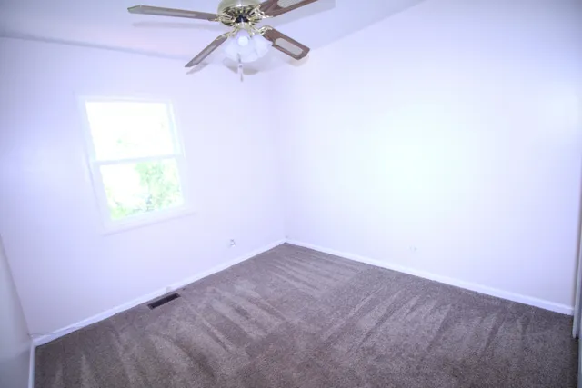 an empty room with a window and a fan