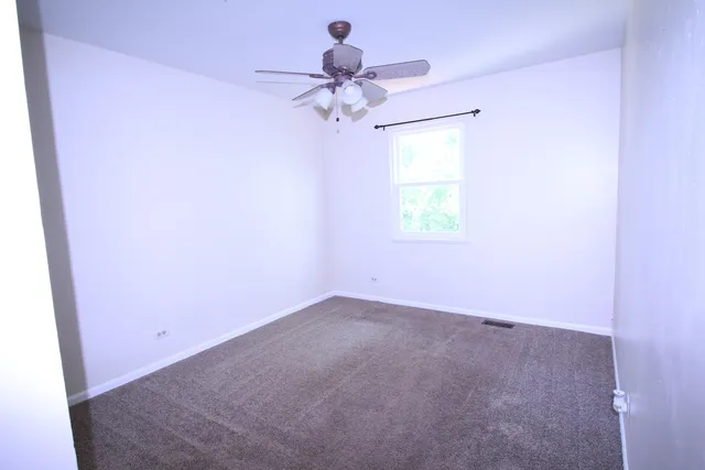 an empty room with a window and a chandelier fan