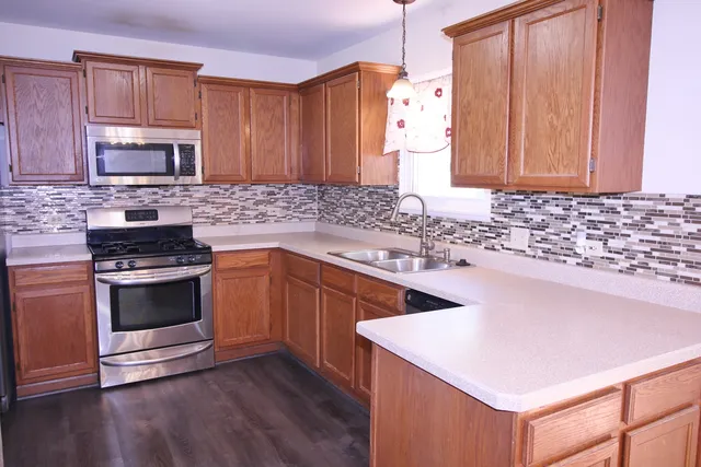 a kitchen with stainless steel appliances granite countertop a sink stove and microwave
