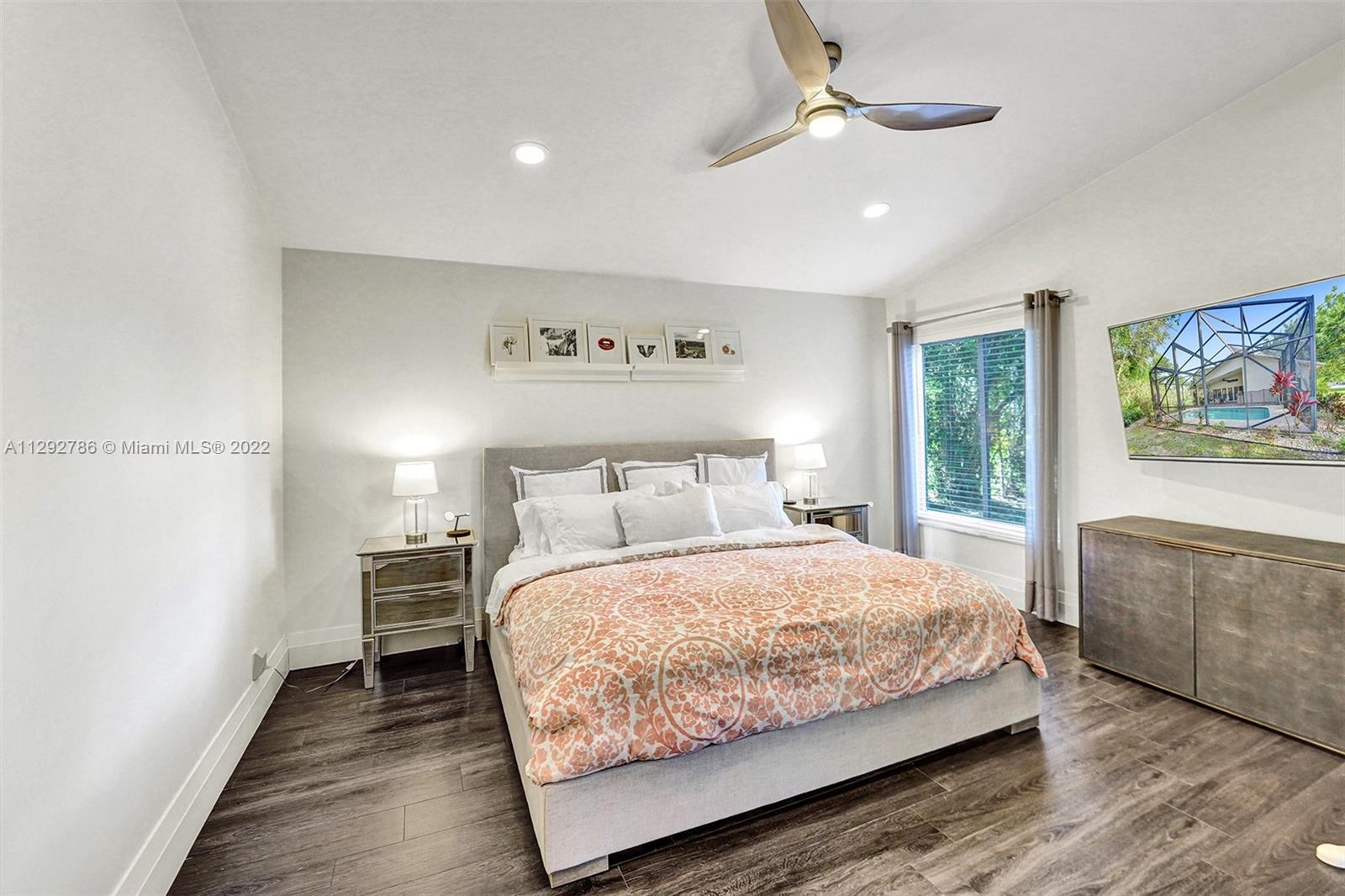 10150 Camelback Lane Boca Raton, FL 33498 - Photo 22 of 67 a bedroom with a large bed chandelier and a window